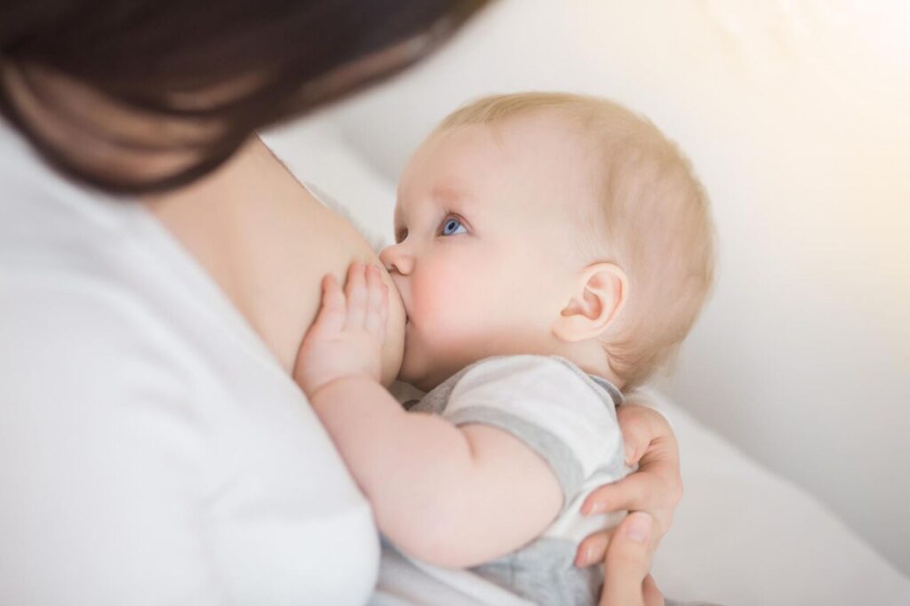 Mother breastfeeding infant in a nursery while preparing to wean.