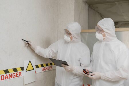 Inspectors in hazmat suits testing for asbestlint in building materials.